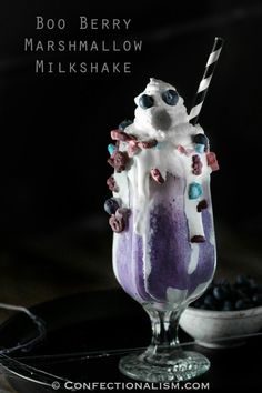 an ice cream sundae with blueberries and milkshake in it on a black plate