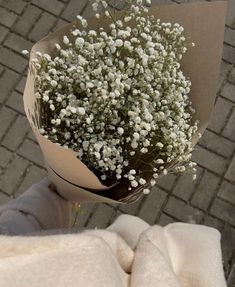 a bouquet of baby's breath sitting on top of a white cloth next to a brick walkway