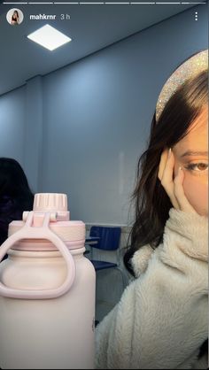 a woman holding her hand to her face next to a white water bottle with a pink handle