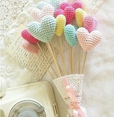 there are knitted hearts on the stick next to an old phone and lace doily