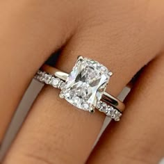 a woman's hand with a diamond ring on top of her finger and an engagement band