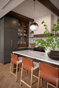 a kitchen with marble counter tops and wooden chairs in front of an island that has plants growing on it