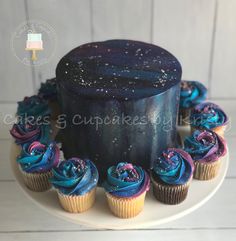 there is a cake with blue frosting and cupcakes on the plate