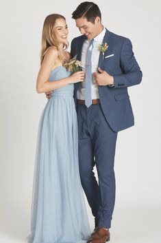 a man in a blue suit standing next to a woman wearing a light blue dress