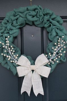 a green wreath with white flowers on the front door