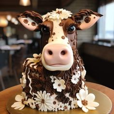 a cake shaped like a cow with brown and white flowers on it's head