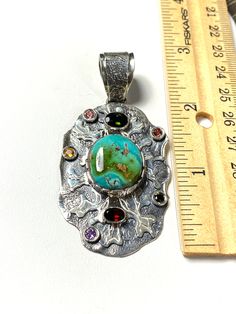 "ARTISAN TURQUOISE TOURMALINE PENDANT Hand-made Sterling Silver 925. Stones used: Turquoise(Nevada), Green Tourmaline, Pink Tourmaline, Red Sapphire, Citrine, Amethyst, Garnet. Height -2 3/4\" (including bail), Width - 1 6/16\" Height - 72mm (including bail), Width - 35mm Unique Handcrafted One-of a-kind Design Pendant Each Piece of Jewelry in my Collection is Absolutely One of a Kind! When you start wearing a piece of my jewelry you will fall in love with it more and more each day and feel that Artisan Turquoise Necklace With Round Pendant, Artisan Turquoise Stone Necklace, Artisan Turquoise Necklace With Stones As Gift, Artisan Turquoise Stones Necklace For Gift, Unique Multi-stone Turquoise Gemstones, Handmade Artisan Turquoise Gemstones, Handmade Multicolor Sterling Silver Turquoise Necklace, Unique Turquoise Stone Pendant Necklace, Turquoise Multi-stone Pendant Necklace As Gift