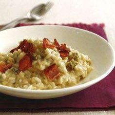 a white bowl filled with oatmeal and topped with tomatoes on top of a red place mat