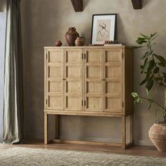 a wooden cabinet sitting on top of a hard wood floor next to a potted plant