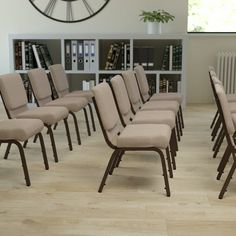 a room filled with lots of chairs next to a book shelf and clock on the wall