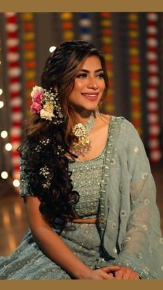 a woman sitting on the floor with flowers in her hair and wearing a blue sari