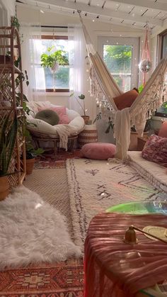 a living room with hammock chairs and rugs on the floor in front of a window