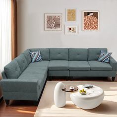 a living room with a sectional couch and coffee table in the middle, along with pictures on the wall