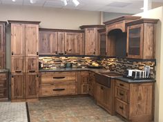 an empty kitchen with wooden cabinets and black counter tops in the middle of the room