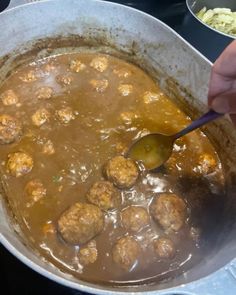 a person is stirring meatballs in a pot