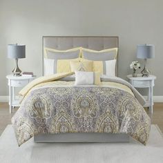 a bed with yellow and gray comforter in a bedroom next to two nightstands