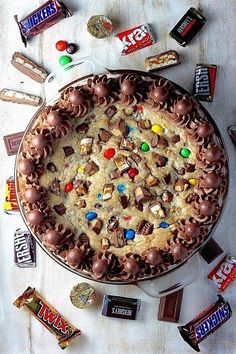 a large cake with lots of candy and candies around it on a white table