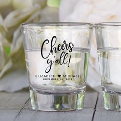 two shot glasses with cheers y'alle written on the front and bottom, sitting next to each other