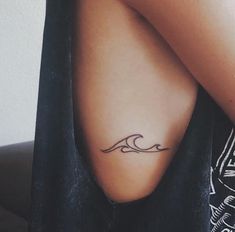 a woman's arm with a tattoo that has a wave on the back of it