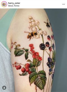 a woman's arm with some flowers and bugs on it, while she is showing off her tattoo