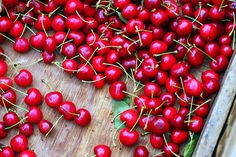 a bunch of cherries sitting on top of a wooden table