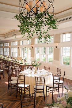 the tables are set with white linens and greenery hanging from the chandelier