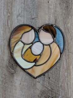 a heart shaped stained glass window hanging on a wooden wall