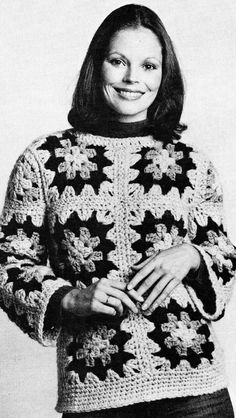 a black and white photo of a woman wearing a crocheted sweater with flowers on it