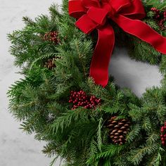 a christmas wreath with red ribbon and pine cones