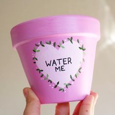 someone holding up a pink cup with water me written on it