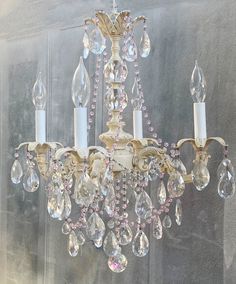 a chandelier with crystal drops hanging from it's sides and two candles in the middle