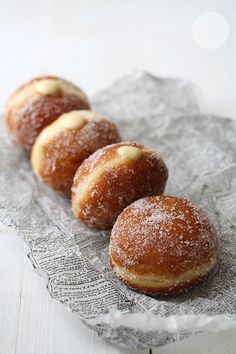 three sugar covered donuts sitting on top of a piece of paper