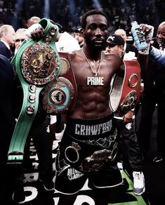 the professional boxer is holding his belt and posing for a photo in front of an audience