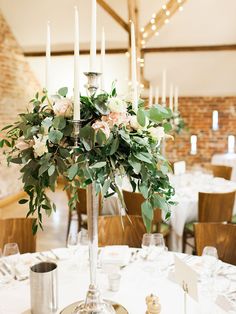 a centerpiece with flowers and candles on a table