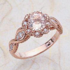 a fancy ring with an oval cut diamond surrounded by smaller round diamonds on a marble surface