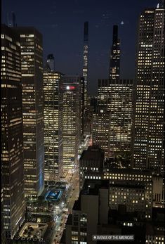 the city is lit up at night with skyscrapers in the foreground and cars on the street below