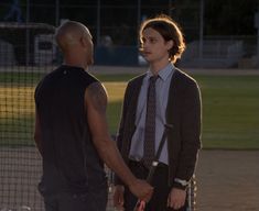 two men standing next to each other on a baseball field