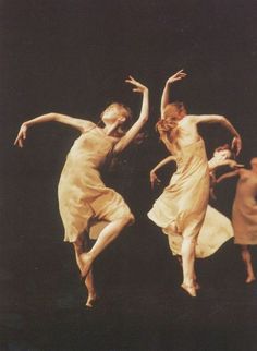 two women in white dresses are dancing on stage