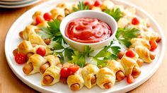 a white plate topped with pigs in a blanket and ketchup