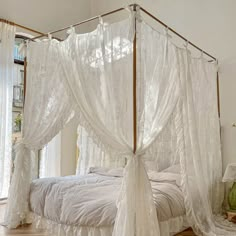 a white bed with sheer curtains on top of it