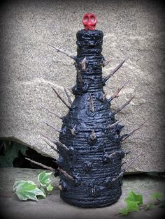 a black bottle with spikes on it sitting next to a stone wall