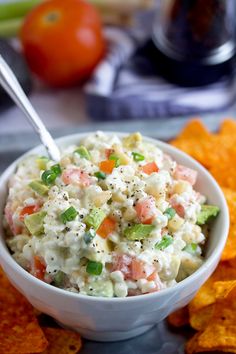 a white bowl filled with food next to tortilla chips