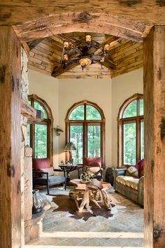 a living room filled with lots of furniture next to tall wooden walls and arched windows