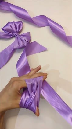 someone is holding purple ribbon in their hand and making it look like they have been tied together