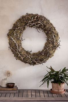 a wreath hanging on the wall next to a potted plant