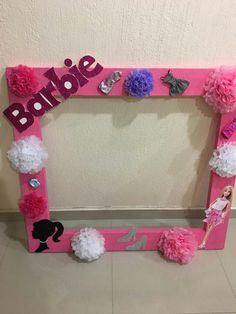 a pink frame with pom poms on the bottom and barbie's name