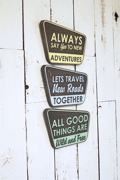 three signs are hanging on the side of a white wooden wall that says, always say up to new adventures let's travel new roads together all good things are wild and free