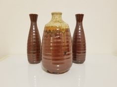 three brown vases sitting on top of a white table