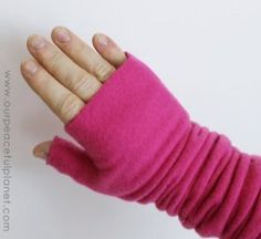 a woman's hand wearing pink fingerless mittens and holding onto a white wall