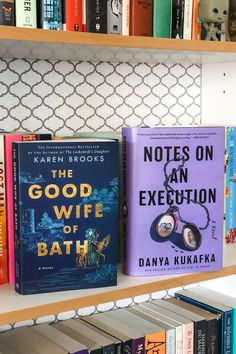 three books on a book shelf in front of a white and blue wall with an iron grate